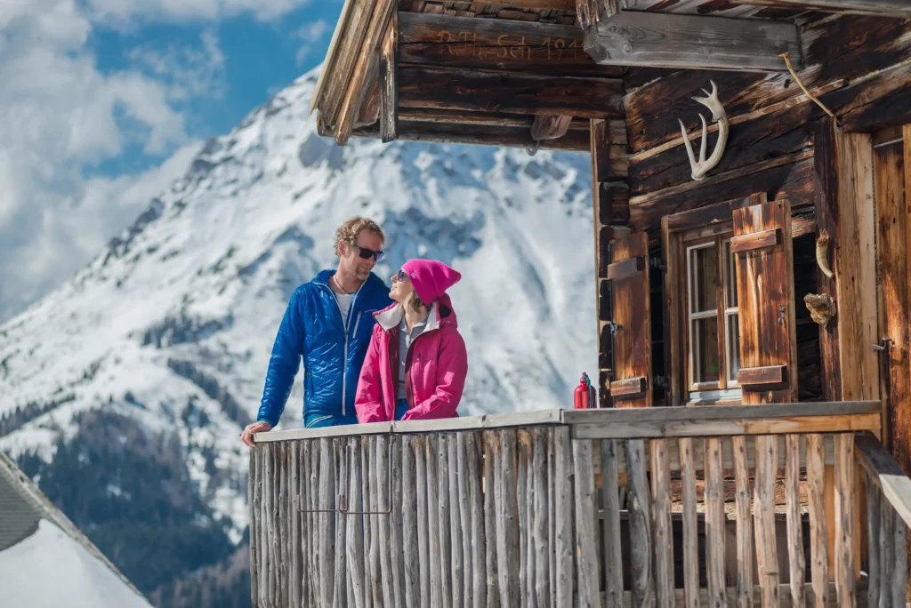 Paar beim Winterurlaub vor einer Holzhütte in Schladming-Dachstein
